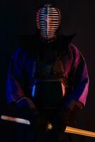 schließen oben Schuss, Kendo Kämpfer tragen im ein Rüstung, traditionell Kimono, Helm üben kriegerisch Kunst mit shinai Bambus Schwert, schwarz Hintergrund. foto