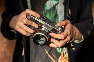 glücklich Hipster Mädchen Herstellung Foto mit retro Kamera auf Stadt Straße. colse-up