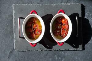 gebacken Kirsche Tomaten im portioniert Pfannen unter Sonnenlicht auf das Tisch, flach legen, schwer Licht, Zutat zum Caprese Appetit anregen foto