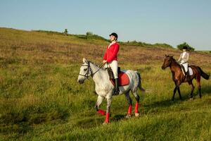 zu Pferd Reiter. zwei attraktiv Frauen Reiten Pferde auf ein Grün Wiese foto