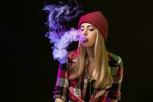 vaping Mädchen. jung Hipster Frau Dampfen e-cig auf Studio auf schwarz Hintergrund. HipHop Stil. schließen hoch. foto