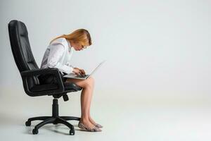 jung Frau Sitzung auf das Stuhl und mit Laptop foto