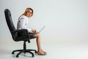 jung Frau Sitzung auf das Stuhl und mit Laptop foto