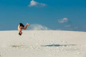 jung Mann Springen auf das Strand mit Weiß Sand und hell Blau Himmel foto