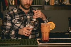 Glas mit Tequila Sonnenaufgang Cocktail auf Bar Zähler auf Hintergrund von Barmann Schließen Flasche foto