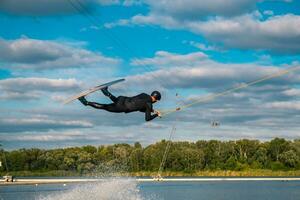 sportlich Mann üben Wakeboard Tricks im Ausbildung aufwachen Park auf Sommer- Tag foto