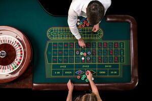 Mann Croupier und Frau spielen Roulette beim das Tabelle im das Kasino. oben Aussicht beim ein Roulette Grün Tabelle mit ein Band messen. foto