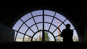 Silhouette von ein mächtig dominierend männlich suchen aus ein Glas Fenster Über das Stadt im Betrachtung oder Betrachtung. Rückseite Aussicht von ein Afroamerikaner Geschäftsmann suchen aus von ein Fenster foto