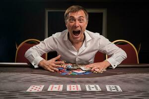 gut aussehend emotional Mann ist spielen Poker Sitzung beim das Tabelle im Kasino. foto