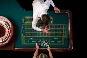 Mann Croupier und Frau spielen Roulette beim das Tabelle im das Kasino. oben Aussicht beim ein Roulette Grün Tabelle mit ein Band messen. foto