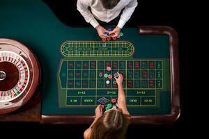 Mann Croupier und Frau spielen Roulette beim das Tabelle im das Kasino. oben Aussicht beim ein Roulette Grün Tabelle mit ein Band messen. foto