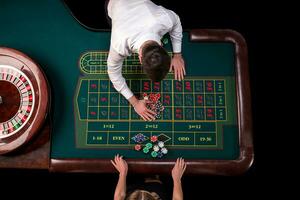 Mann Croupier und Frau spielen Roulette beim das Tabelle im das Kasino. oben Aussicht beim ein Roulette Grün Tabelle mit ein Band messen. foto