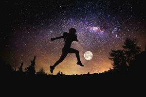 Spieler Fußball Mann Springen beim das Nacht sternenklar Himmel Hintergrund. gemischt Medien foto