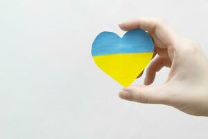 das Konzept von Ende das Krieg im Ukraine. Herz im das Farben von das Flagge von Ukraine im weiblich Hände. foto
