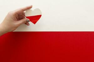 Papier Herz im das Farben von das Flagge von Polen im weiblich Hände. foto