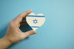 das Konzept von Ende das Krieg im Israel. Herz im das Farben von das Flagge von Israel im weiblich Hände. foto