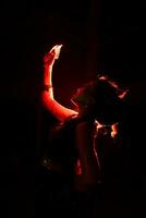 Silhouette von ein weiblich Tänzer halten Schmuck im das Mitte von das Stille von das Nacht mit rot Licht foto