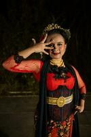 ein indonesisch Tänzer im rot Kleider und ein schwarz Schal posiert mit sehr lockig und schön Finger foto