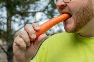 ai generiert bärtig Mann genießen gesund Karotte Snack foto
