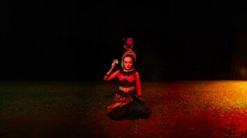 ein weiblich Tänzer im ein rot Kostüm saß im das Stille von das Nacht welche gestärkt das Traurigkeit foto