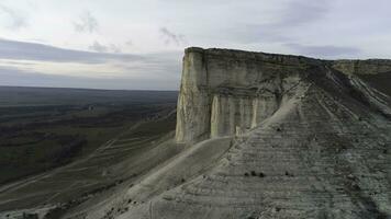 Antenne oben viewfor atemberaubend Weiß Cliff in der Nähe von Grün Senke auf Schön, wolkig Himmel Hintergrund. Schuss. Weiss, hoch Felsen Cliff in der Nähe von das Feld mit Grün Gras. foto