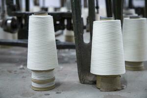 Weiß Baumwolle Spulen von Fäden auf das industriell Stricken Fabrik Fußboden foto