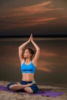 Yoga beim Sonnenuntergang auf das Strand. foto