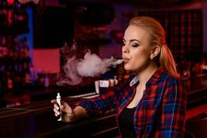 jung ziemlich Frau Rauch ein elektronisch Zigarette beim das Dampfen Bar foto