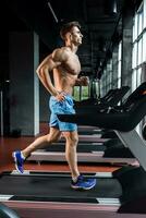 jung Erwachsene Mann Laufen auf Laufband im Fitnessstudio foto