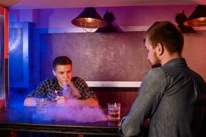 zwei jung Männer Rauch elektronisch Zigaretten im ein vapebar foto