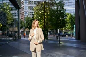 Porträt von jung zuversichtlich korporativ Frau im Beige Anzug, Stehen auf Straße im ihr Geschäft Outfit, suchen selbstbewusst foto