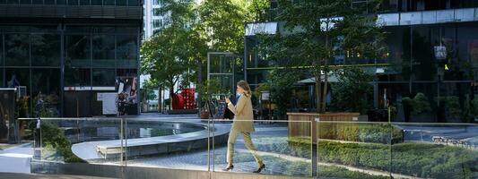 Silhouette von korporativ Frau im passen Gehen entlang Stadt Center in der Nähe von Büro Gebäude foto