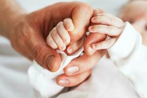 schließen oben Foto von Vater halten Neugeborene Baby Hand.