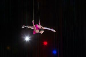 Zirkus Künstler Akrobat Leistung. das Mädchen führt aus akrobatisch Elemente im das Luft. Zirkus Turner auf das Bühne foto