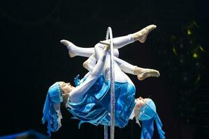 zwei Akrobat Mädchen Show ein Zirkus Nummer auf ein dunkel Hintergrund. akrobatisch Leistung. foto