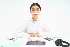 Geschäft und Büro arbeiten. jung Frau Sitzung beim Arbeitsplatz, täuschen um, hält Stift mit Lippen und zeigt an komisch Gesichter, Weiß Hintergrund foto