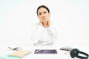 müde asiatisch Frau, Büro Dame sitzt hinter ihr Schreibtisch, hat zurück Schmerz, massieren ihr Schulter, müde nach arbeiten, Weiß Hintergrund foto