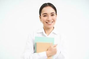erfolgreich jung asiatisch Frau, Lehrer mit Notizbücher, suchen zuversichtlich und lächelnd, Weiß Studio Hintergrund foto