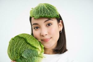 schließen oben Porträt von schön und gesund vegan Frau, halten Kopfsalat, hat Kohl führen auf Kopf, Weiß Hintergrund foto