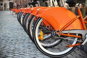 orangefarbene Stadtfahrräder, die in einer Reihe stehen foto