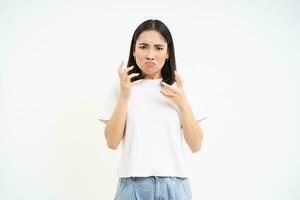 Bild von wütend asiatisch Frau, Zusammenpressen ihr Hände und suchen frustriert, besoffen aus, Stehen isoliert auf Weiß Hintergrund foto
