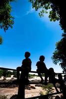 kleiner Junge sitzt auf einem Zaun am Wasserfall Khone Phapheng oder Mekong in Champasak südlich von Laos, einem der größten und schönsten Wasserfälle in Asien und der Welt foto