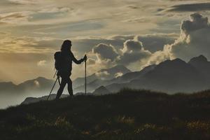 Einsamkeit auf den Alpen spazieren. eine Frau mit dem Hintergrund abstrakter Berge in den Wolken foto