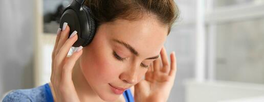 Gesicht von schön Frau im kabellos Kopfhörer, genießt Klang, hört zu zu Musik- im kabellos Kopfhörer foto