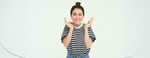 Porträt von Frau reagiert zu tolle Nachricht, klatscht Hände und lächelt, zufrieden durch etw, steht Über Weiß Hintergrund foto