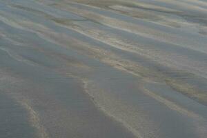 schwarz vulkanisch Sand Strand mit Welle Muster foto