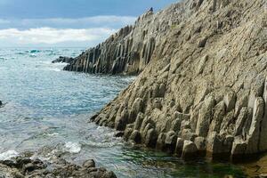 natürlich Landschaft mit ein schier Cliff gefaltet säulenförmig Basalt auf das Strand foto