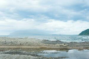 felsig Strand gemacht von säulenförmig Granit, gehärtet Lava, ähnlich Waage oder Kopfsteinpflaster Gehweg, Küste von Kunaschir Insel foto