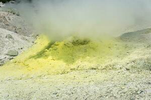 Gelb Kegel von kristallisiert Schwefel um ein Rauchen Solfatara auf das Steigung von ein Vulkan foto