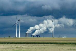 Wind Turbinen und industriell Rohre mit Rauch auf ein wolkig Tag im Deutschland foto